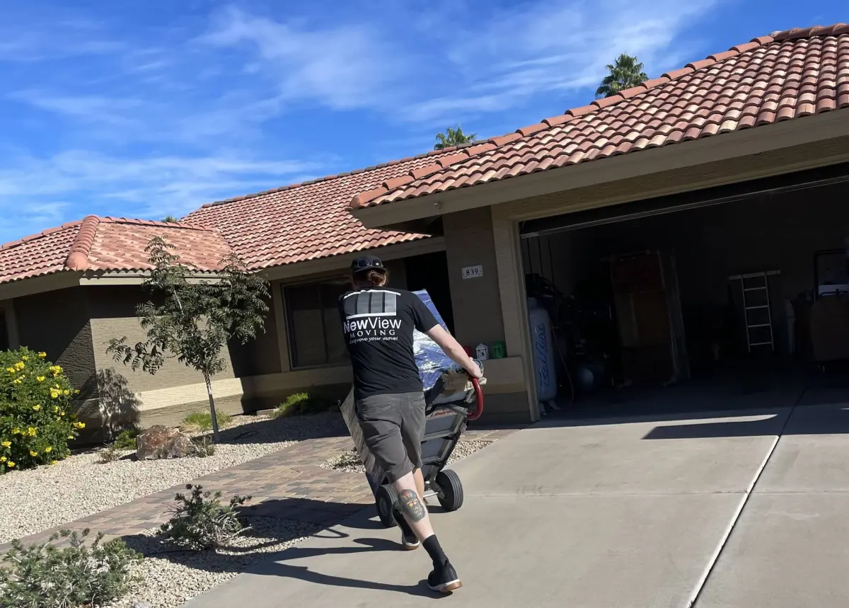 A NewView mover wheels a load up a driveway toward a garage