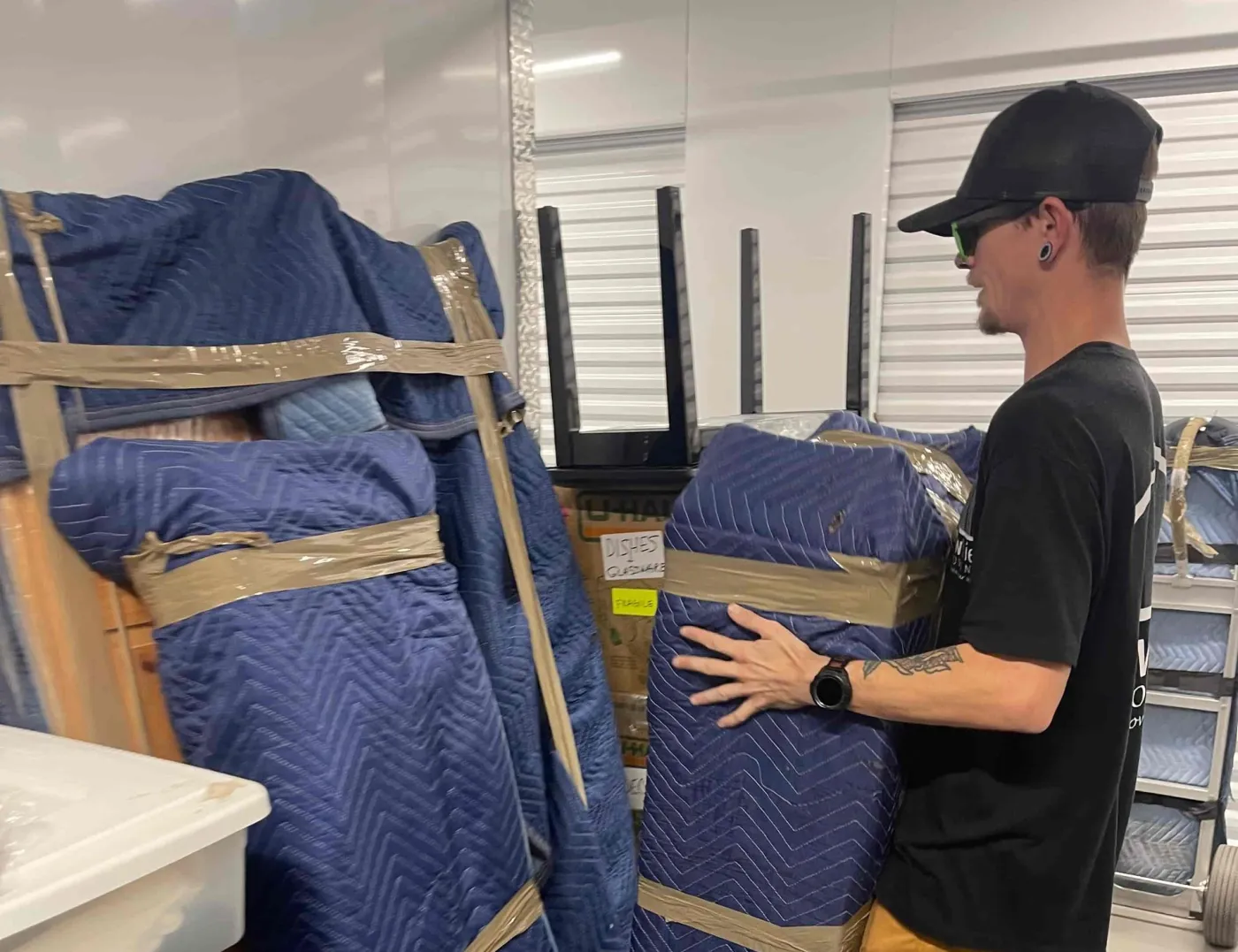 A NewView mover stacks furniture wrapped in blue moving pads