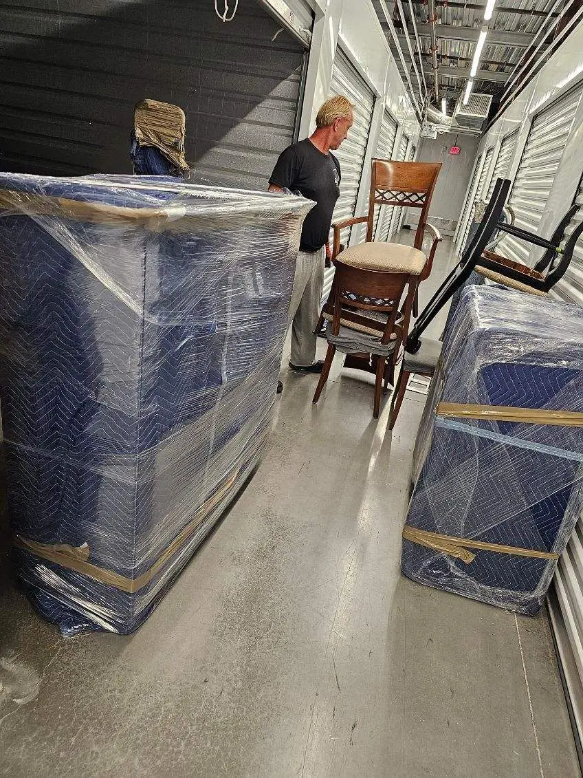 Padded and shrink-wrapped furniture stored in a clean storage corridor